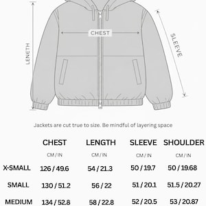 Op de afbeelding: Een lijntekening van een jack met capuchon, verlaagde schouders en een ritssluiting aan de voorzijde. Het diagram toont labels voor schouder-, borst-, lengte- en mouwmaten. Een tabel geeft de afmetingen in cm voor maten X-Small tot 2X-Large.