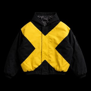 Pode incluir: Um casaco com capuz preto e amarelo com um grande padrão em forma de X na parte frontal. A peça inclui uma carcela central, mangas compridas com punhos canelados e um forro interior acolchoado visível na zona da gola.