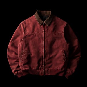 May include: A deep red canvas jacket featuring a dark brown corduroy collar, a full-length front zipper closure, two slanted welt pockets at the waist, and ribbed knit cuffs and hem. The garment has a western-style yoke across the chest.