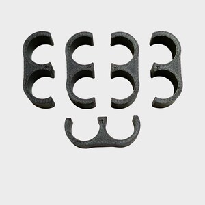 May include: A set of six dark gray, semi-circular clips. The clips are arranged in two rows, with three clips in the top row and three in the bottom row. The clips appear to be made of a 3D-printed material.