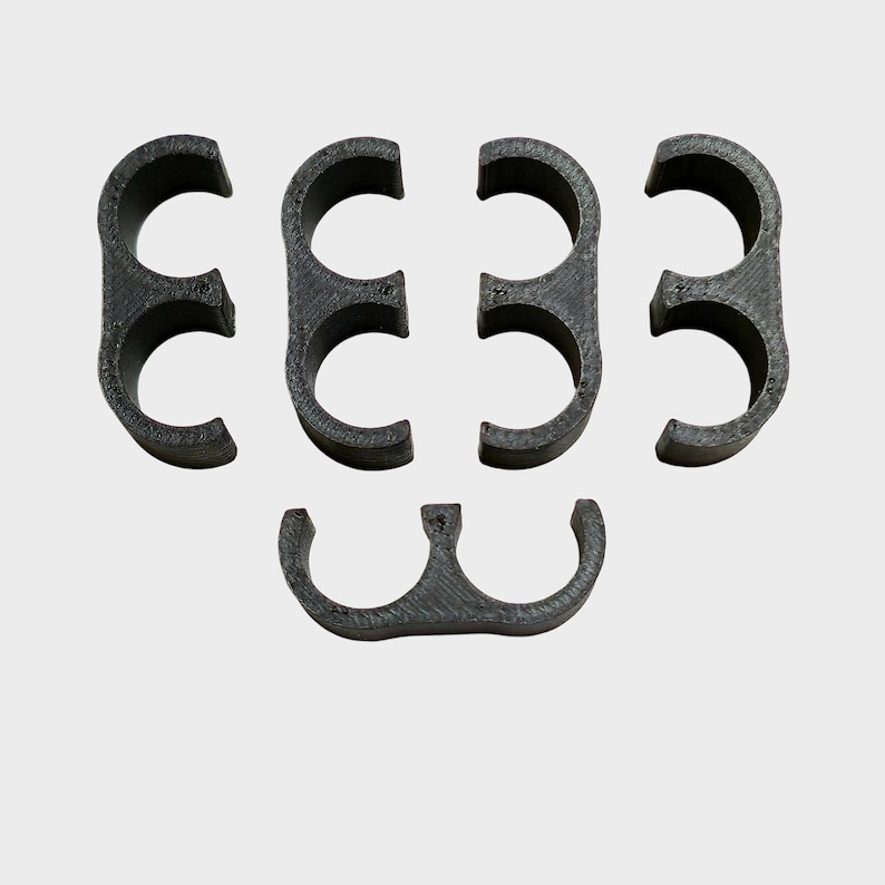 May include: A set of six dark gray, semi-circular clips. The clips are arranged in two rows, with three clips in the top row and three in the bottom row. The clips appear to be made of a 3D-printed material.