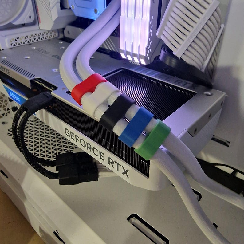 May include: Close-up of a computer's internal components, featuring white cables secured with colorful clips. The text "GEFORCE RTX" is visible on a component. The clips are red, white, black, blue, and green.
