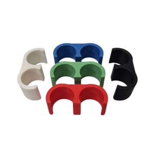 May include: A collection of colorful, double-holed clips in white, blue, green, red, and black. Each clip has a curved design with two circular openings. The clips are arranged in a visually appealing manner, showcasing their various colors.
