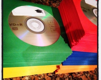 May include: A stack of green, red, blue, orange, and yellow DVD-R discs. The top disc has a graduation cap sticker and the text "VD+R".