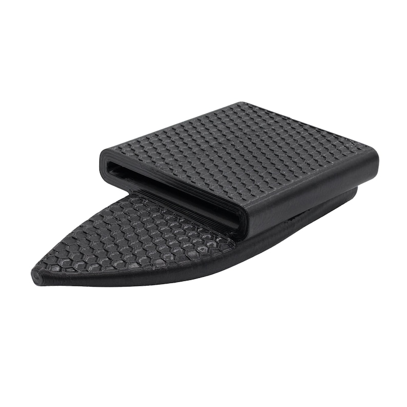 Puede incluir: Hebilla de correa negra con superficie texturizada y dise&ntilde;o geom&eacute;trico. La hebilla tiene una secci&oacute;n superior rectangular y una secci&oacute;n inferior triangular, ambas con un patr&oacute;n hexagonal repetido.