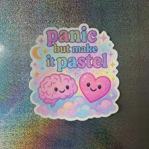 May include: Pastel pink and blue sticker with a brain and heart with smiling faces. The sticker says "panic but make it pastel".