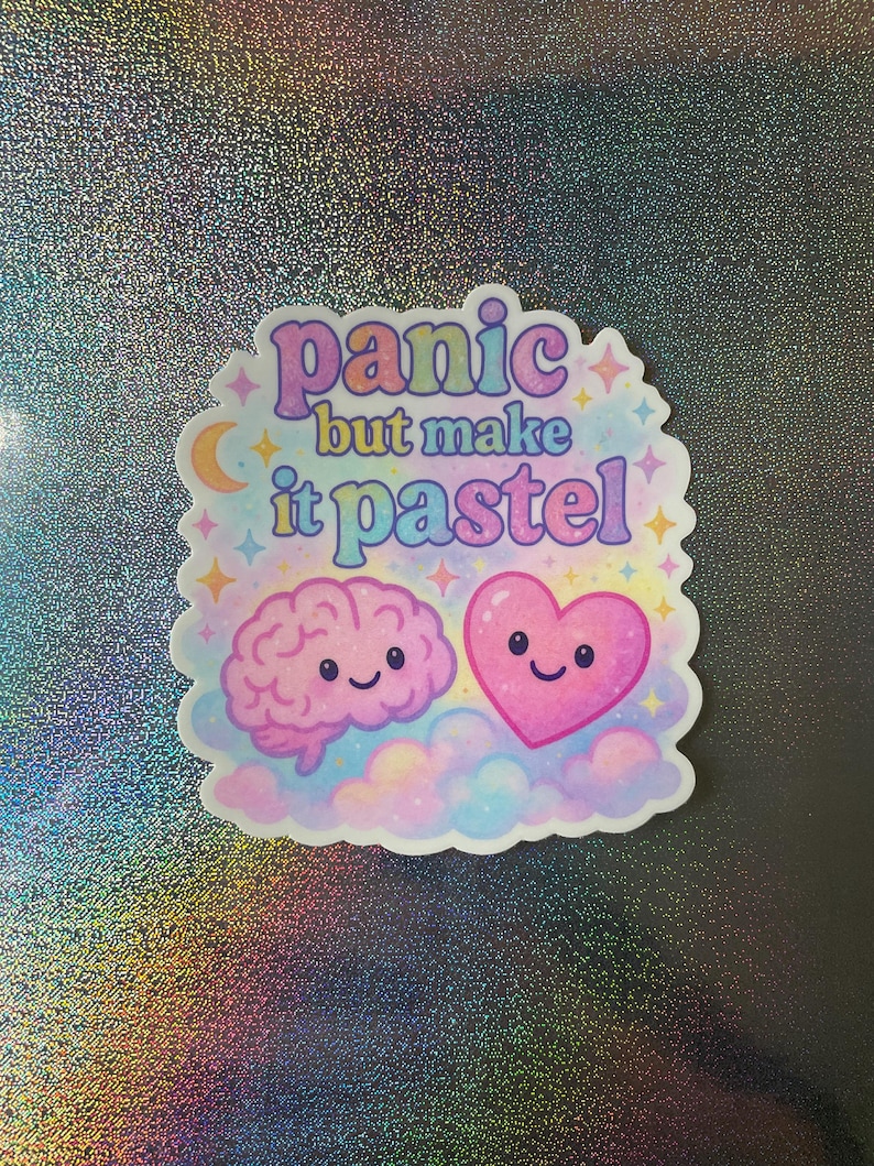 May include: Pastel pink and blue sticker with a brain and heart with smiling faces. The sticker says "panic but make it pastel".
