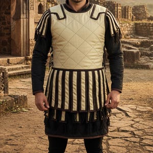 May include: A cream-colored quilted vest with brown trim and a striped skirt, part of a historical costume. The vest has a diamond pattern, and the skirt features vertical stripes. Black sleeves and pants complete the outfit, suitable for historical reenactments or themed events.