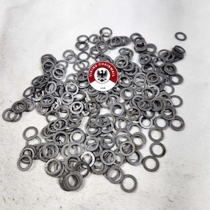 May include: A large pile of silver metal rings, likely for chainmail, with a red and black logo in the center that reads "Viking Chainmail USA".