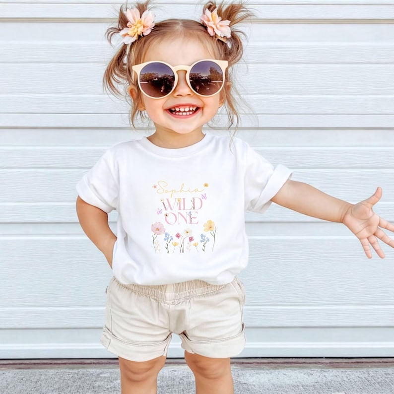 May include: A white ceramic mug with a black handle and the text "But First, Coffee" in a bold, black font. The mug is set against a blurred background, suggesting a cosy setting.
