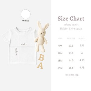 May include: White infant t-shirt with size chart. The chart shows measurements in inches for sizes 6M to 24M. A stuffed bunny and wooden letters are next to the shirt. The text on the chart reads "Infant Tshirt Rabbit Skins 3322".