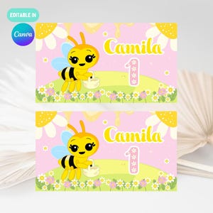 May include: Two rectangular party invitations featuring a cartoon bee holding a basket. The invitations have a pink background with the name "Camila" and the number "1". The design includes flowers and a daisy border.