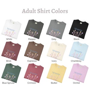 May include: A selection of adult sweatshirts in colours such as white, black, and grey. Each top features the text "Mommy of the Wild One" with floral and butterfly designs. The image is labelled "Adult Shirt Colours".