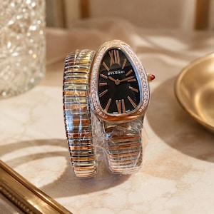 May include: A Bvlgari Serpenti watch with a teardrop-shaped case, a black sunburst dial, and rose gold Roman numeral indices. The bezel is set with diamonds, and the watch features a flexible, multi-coil bracelet in alternating rose gold and silver tones.