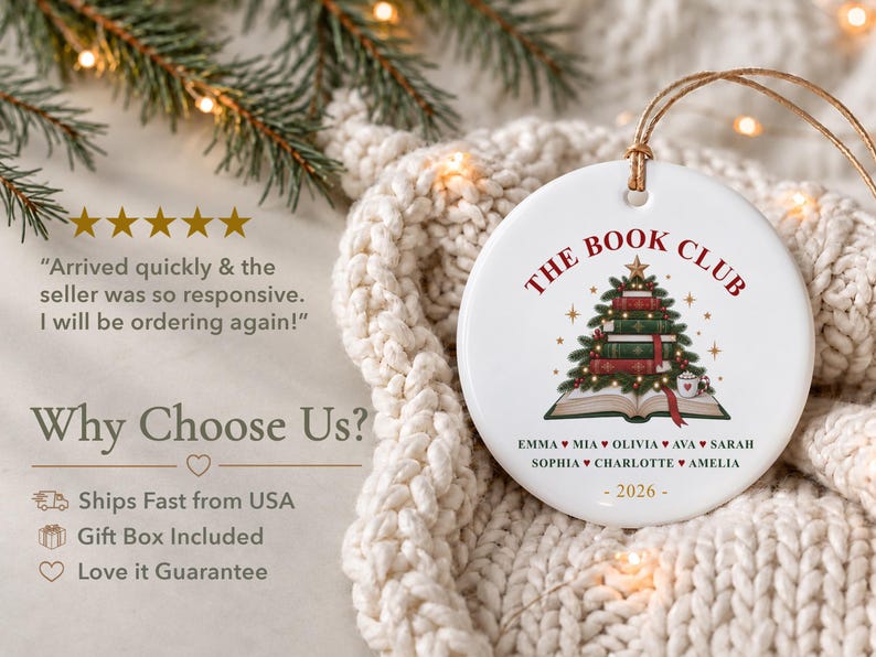 May include: A round white ceramic ornament featuring a graphic of a Christmas tree made of stacked books atop an open book. The text reads THE BOOK CLUB, followed by a list of names separated by hearts and the year 2026 at the bottom.