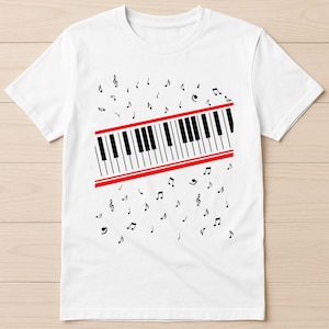 May include: White t-shirt with a piano keyboard design. The keyboard has black and white keys, framed by red lines. Black musical notes are scattered around the keyboard. A music-themed casual tee.