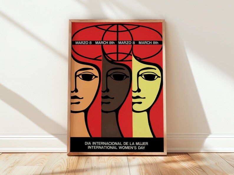 May include: A framed poster featuring a red background with three stylized faces in orange, dark brown, and yellow. Above the faces is a black globe outline. Text reads: MARZO 8 MARCH 8th and DIA INTERNACIONAL DE LA MUJER INTERNATIONAL WOMEN'S DAY.