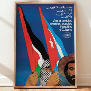 May include: A framed poster with a blue background features flags of Palestine and Cuba. The poster includes text in Arabic and Spanish, with the phrase "Viva la amistad entre los pueblos Palestino y Cubano."