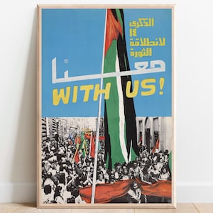 Peut inclure: Affiche encadrée avec un fond de ciel bleu et les mots "WITH US!" en jaune. L'affiche présente du texte arabe et un drapeau avec des rayures noires, blanches, vertes et rouges. Une foule de personnes avec des drapeaux est visible en bas.