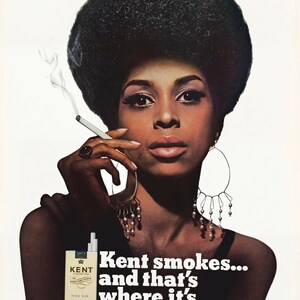 May include: Vintage advertisement featuring a woman with a large afro, wearing large hoop earrings, and smoking a cigarette. The ad includes a pack of Kent cigarettes and the text "Kent smokes... and that's where it's at."