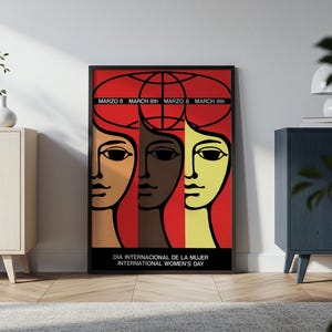 May include: A framed rectangular poster featuring three stylized faces in tan, brown, and yellow against a red background. Above the faces is a globe graphic and the text MARZO 8 MARCH 8th. Below is the text DIA INTERNACIONAL DE LA MUJER INTERNATIONAL WOMEN'S DAY.