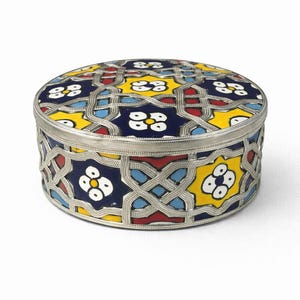 Peut inclure: Une boîte décorative ronde avec un cadre et un couvercle en métal argenté. Le couvercle et les côtés présentent un motif de mosaïque coloré avec des motifs floraux bleus, jaunes, rouges et blancs. La boîte mesure environ 7,6 cm de diamètre.