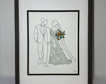 May include: Framed artwork featuring a line drawing of a couple in wedding attire. The bride's dress is composed of sea glass, and she holds a bouquet of flowers. The artwork is set against a white background and framed in a dark gray wooden frame.