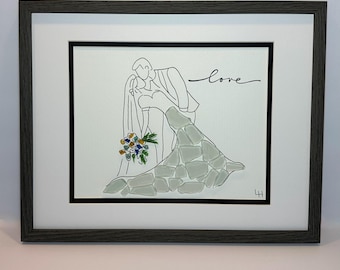 May include: Framed artwork featuring a line drawing of a couple embracing, with the word "love" in cursive. The bride's dress is textured with gray stones, and she holds a bouquet. The frame is dark gray.