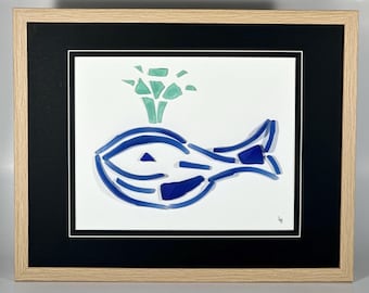 May include: A framed artwork featuring a blue whale made of glass mosaic tiles. The whale is swimming with a green and blue glass mosaic spray of water above it.