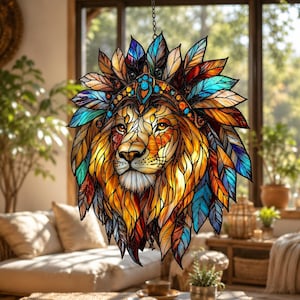 Könnte beinhalten: Ein Buntglas-Sonnenfänger mit einem Löwenkopf und einer leuchtenden Mähne aus bunten Federn in Blau-, Orange- und Gelbtönen. Der Löwe trägt einen dekorativen Kopfschmuck mit blauen Akzenten, alles eingefasst in dunkle Metalllinien.