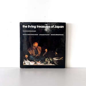 May include: A black book titled "The Living Treasures of Japan" with a photo of a person working on pottery on the cover.