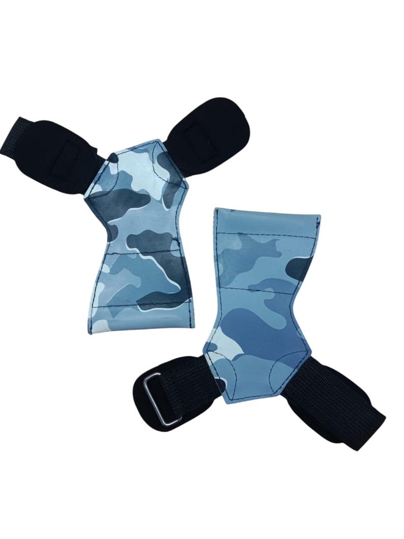 May include: Two weightlifting grips with a blue camouflage pattern. Each grip has a black wrist strap with a metal buckle and a padded area for the palm. The grips are designed to protect the hands during workouts.