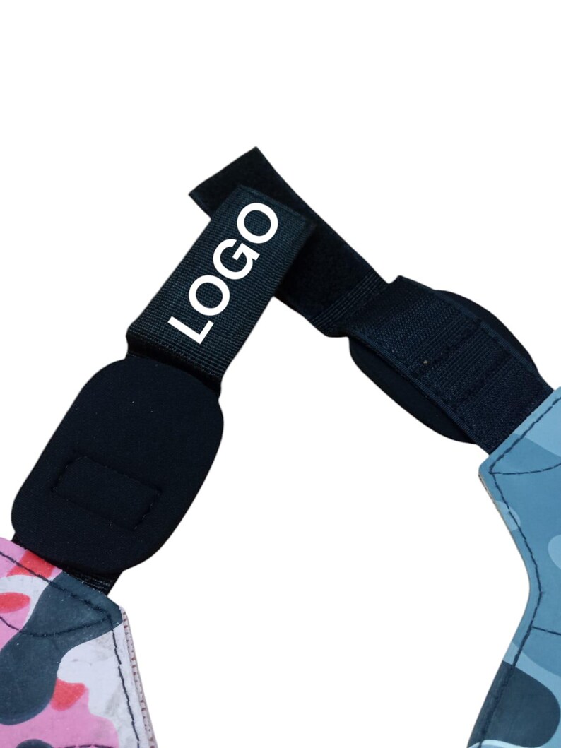 May include: Black adjustable strap with the white text "LOGO". The strap is connected to a pink and black camouflage pattern and a blue camouflage pattern. The strap has a velcro closure.