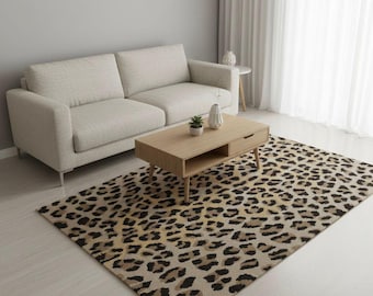 Pode incluir: Uma sala de estar com um sofá bege, uma mesa de centro de madeira clara e um tapete com estampa de leopardo. O tapete retangular tem um padrão de manchas pretas e marrons sobre um fundo bege. O ambiente tem uma paleta de cores neutras.