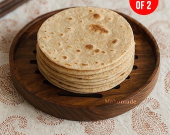 Puede incluir: Una pila de pan plano marrón claro sobre una bandeja redonda de madera. La bandeja tiene un acabado marrón oscuro y un diseño tallado. Un círculo rojo con el texto "PACK OF 2" es visible. La bandeja está sobre una tela blanca con un estampado de cachemira.