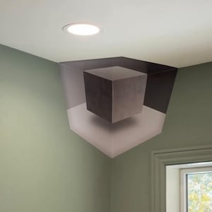 Puede incluir: Un mural de ilusión óptica que presenta un cubo gris oscuro suspendido dentro de una estructura de cubo gris más grande y claro. La obra de arte está pintada en la esquina de una habitación con una pared verde claro y un techo blanco, iluminada por una luz empotrada.