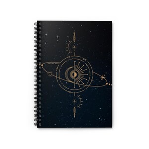 Peut inclure: Cahier à spirales avec un motif céleste. La couverture présente une illustration dorée de planètes, d'étoiles et d'un croissant de lune sur un fond bleu foncé étoilé. Le cahier a une reliure à spirales noire.