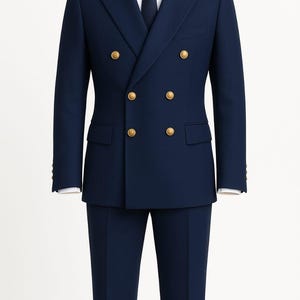 May include: A navy blue double-breasted suit with gold buttons. The suit includes a matching navy tie and a white dress shirt. The jacket has two rows of buttons and a tailored fit. The suit is a classic formal wear ensemble.
