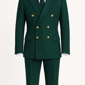 Könnte beinhalten: Ein dunkelgrüner Doppelreiher-Anzug mit goldenen Knöpfen, einem weißen Hemd und einer passenden grünen Krawatte. Der Anzug umfasst eine Jacke mit zwei Knopfreihen und eine passende Hose. Es ist klassische formelle Kleidung.