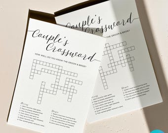 May include: Two white paper cards with the text "Couple's Crossword" in elegant script. The cards feature crossword puzzles with clues related to the bride and groom. The text "How well do you know the groom & bride?" is also visible.