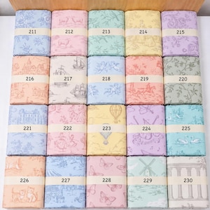Op de afbeelding: Een collectie van twintig gevouwen stofstalen gerangschikt in een raster, elk met een uniek toile de jouy-patroon in diverse pastelkleuren. Elke staal is vastgezet met een papieren band voorzien van een nummer van 211 tot 230.