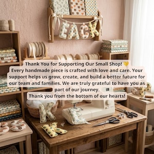 Op de afbeelding: Een naaiwerkruimte met een beige naaimachine op een houten tafel, omringd door stapels stof, rollen lint en pluche stoffen letters die het woord PEACE vormen. Een bedankbriefje is over de afbeelding geplaatst om dankbaarheid uit te drukken.