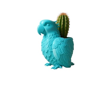 Pode incluir: Um vaso em forma de papagaio turquesa com um cacto. O vaso tem desenhos detalhados de penas e olhos. O cacto é verde com espinhos castanhos. O vaso é feito de um material liso e é um item decorativo.