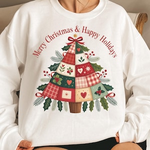 Peut inclure: Sweat-shirt blanc avec un motif d'arbre de Noël en patchwork. L'arbre est composé de carrés rouges, verts et crème, décoré de cœurs, de houx et d'une étoile. Le texte "Merry Christmas & Happy Holidays" est en rouge.