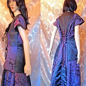 May include: A purple and black dress with a lace-up back and a fitted bodice. The dress has a long skirt with a ruffled hem.