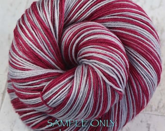 Könnte beinhalten: Ein rundes Garnknäuel mit abwechselnden Strängen in tiefem Magenta und Hellgrau. Das Garn ist kreisförmig aufgewickelt. Der auf das Bild gelegte Text lautet: SAMPLE ONLY. Colors may vary due to fiber content.
