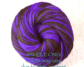 Könnte beinhalten: Ein rundes Garnknäuel mit einem melierten Muster aus tiefvioletten und dunkelbraunen Fasern, die miteinander verzwirnt sind. Der Text SAMPLE ONLY. Colors may vary due to fiber content. ist in hellblauer Schrift unten auf dem Garn abgedruckt.