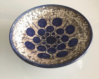 May include: A small, round ceramic bowl with a blue and white geometric design. The bowl has a crackled glaze and a white background.