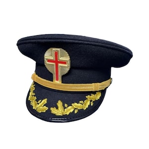Könnte beinhalten: Eine dunkelmarineblaue Mütze mit einem goldenen Kreuzemblem und goldenen Verzierungen. Die Mütze hat ein goldenes Band und goldene Blattstickereien am Rand. Es handelt sich wahrscheinlich um eine zeremonielle oder formelle Kopfbedeckung.