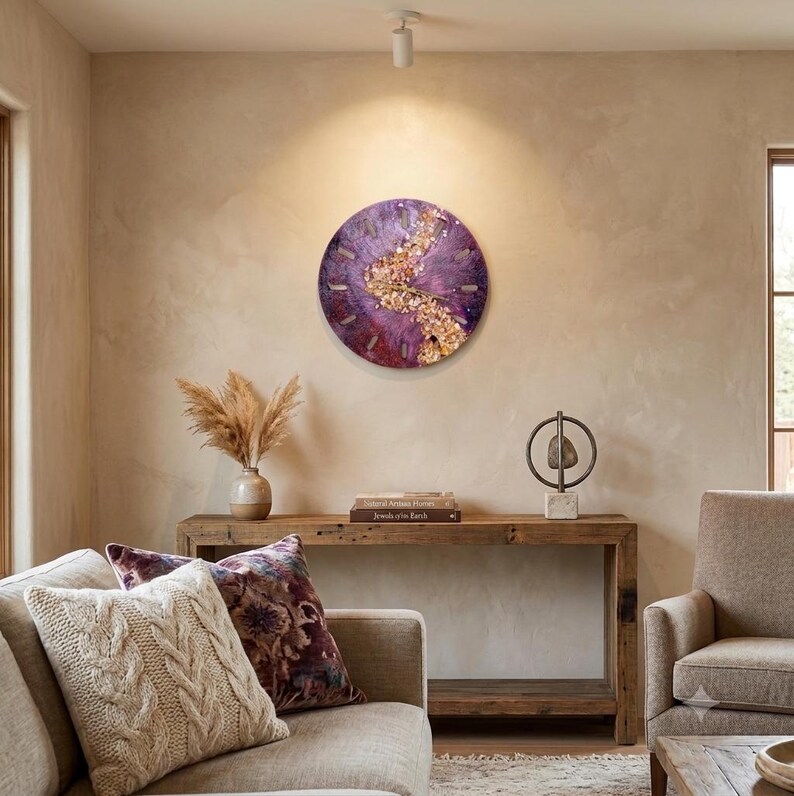 A circular wall clock featuring a deep purple resin base with a central, textured band of gold-toned metallic flakes and crystals. The clock face includes simple, thin gold-colored hour markers and matching central hands for timekeeping.
